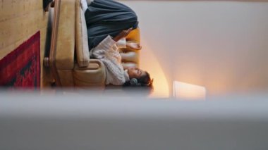 Sakin kız evde koltuğu dinlendiriyor. Kıvırcık saçlı esmer, kulaklık dinliyor. Lamba ışığında film seyrediyor. Beyaz odadaki Afrikalı kadın internet haberlerini tarıyor.