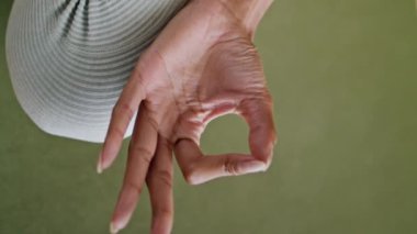 Kapanış kızı içeride yoga meditasyonu yapıyor. İşaret parmağını birbirine bağlayan tanınmayan bir kadın lastik halıyı dikey oturtuyor. Sportif kadın elleri paspasda gyan mudra hareketi yapıyor.. 