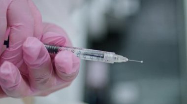 Kadın müşteriye enjekte etmeden önce doktor ellerinde kolajenle tıbbi şırınga ile dikey görüntüler tutuyor. Bilinmeyen kozmetik uzmanı klinikte güzellik gençleştirme için ilaç hazırlıyor.
