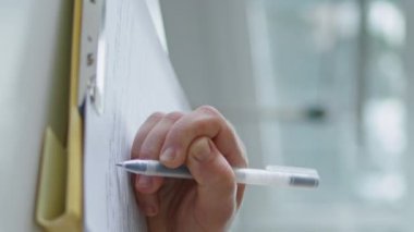Masaya el yazısı yazan bir kadın dikey olarak kapatıyor. Kalem doldurma formu olan bilinmeyen bir kız belge sözleşmesi randevusu yazıyormuş. Evrak işlerinde çalışan tanınmamış zarif bir iş kadını.