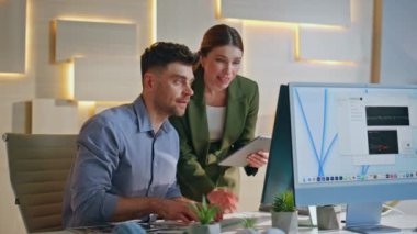 Yaratıcı ajanstaki bilgisayarda çalışan tasarımcılar. Deneyimli kadın takım lideri, erkek çizimciye ofiste tasarım projesinde yardım ediyor. İki gülümseyen iş arkadaşı yeni bir çözüm arayan fikirleri tartışıyor.