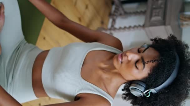 Розслаблена Жінка Розтягує Ноги Спальні Кучерява Брюнетка Слухає Музику Медитуючи — стокове відео