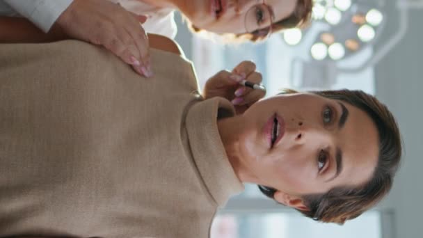 Profesjonalny Kosmetyczka Pokazując Twarzy Wynik Atrakcyjnej Klientki Patrząc Lustro Pionowo — Wideo stockowe