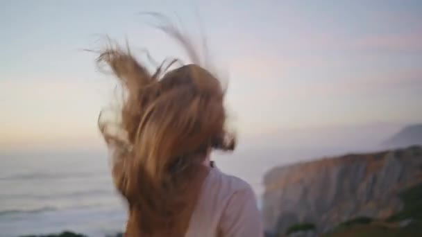 夕方の丘の景色を眺めるハッピーな女性 アウトドア旅行で人生の自由を楽しむ髪に触れるケアフリーの少女 ロマンチックな気分を持つ美しい長髪モデル ホリデーレジャーコンセプト — ストック動画