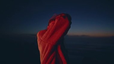 Neon light kız gece dans eden plaj partisi yakın çekim. Sıska kadın şık kıyafetler içinde gösteri yapıyor. Uzun saçlı manken, deniz kıyısında yazın hareket eden cesedin keyfini çıkarıyor. Cazibeli bayan rahat kırmızı çoraplarla dans ediyor.