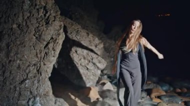 Gece partisinde dans eden göz kamaştırıcı kadın. Siyah elbiseli seksi, uzun saçlı kadın kameraya bakıp el sıkışıyor. Havalı dansçı kız duman bulutu içinde parti veriyor açık hava festivali ışığında yalnız poz veriyor. 