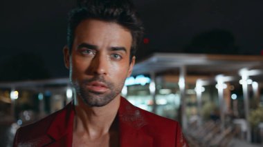 Erkeksi, çekici bakışları olan kameralı bir adam. Gecenin geç saatlerinde zarif kırmızı ceketli vahşi erkek modelin portresi. Tıraşsız İspanyol adam, hafta sonunun tadını çıkar..