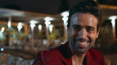 Açık hava partisinde şampanya içen zarif bir beyefendi. Yakın plan. Mutlu İspanyol maçosu hafta sonu arkadaşça takılmanın tadını çıkarıyor. Tıraşsız gülümseyen adam havuz başında alkolle serinliyor..