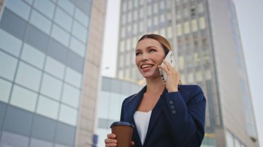 Güzel bayan patron şehir caddesinde kahve fincanı ile yürümeyi çağırıyor. Rahatlamış gülümseyen iş kadını iş yerinde arkadaşlarıyla dışarıda konuşuyor. Gezintide akıllı telefonlardan konuşan mutlu, başarılı kadın..