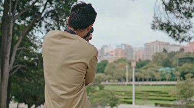 Adam profesyonel kamerayla şehir manzarasını çekiyor. Tanımlanamayan fotoğrafçı hafta sonu gezisinde fotoğraf çektiriyor. Rahat adam parktaki modern fotoğraf makinesinde fotoğraf izliyor.