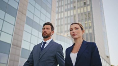 Şirket çalışanları sokakta yürürken gülümsüyor. Başarılı iş çifti şehir merkezinde yürürken kameraya işaret ediyor. Modern kasaba sokaklarına birlikte çıkan kendine güvenen zarif iş adamları.