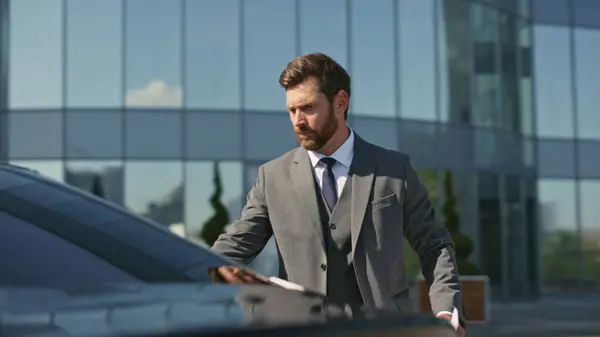 Assistant open car door to beautiful lady boss close up. Bearded businessman meeting woman corporate partner arrived on luxury automobile. Elegant man showing business documents to female manager.