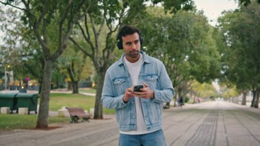 Kulaklıklı adam hafta sonu yürüyüşünde akıllı telefon uygulamasını açıyor. Gülümseyen İspanyol adam Park Caddesi 'nde kablosuz kulaklıkla müzik dinliyor. Modayı takip eden yakışıklı erkek öğrenci ritmik sesin tadını çıkarıyor.