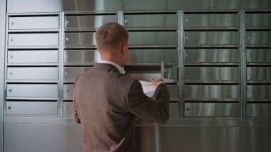 Başarılı bir adam ofis binasını kontrol ediyor. Koridordaki metal posta kutusu dolabından mektup alan yakışıklı bir adam. Çağdaş salonda takım elbiseli bir işadamı posta okuyor..