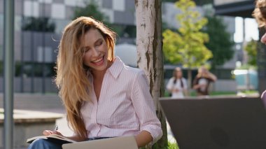 Çekici kadın dışarıda ders çalışıyor, arkadaşlarıyla yakın çekim konuşuyor. Gülümseyen serbest ortaklar şehir parkında bilgisayarlara uzaktan bakıyorlar. Arkadaş canlısı iş kadını not alıyor. Sokakta sohbet eden meşgul bir çift..