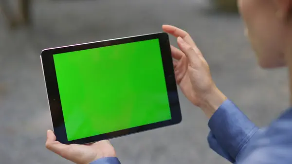 Hand touching mockup tablet with green screen on street closeup. Manager working remotely tapping chroma key pad outdoors. Unknown girl entrepreneur videocalling partner watch digital computer online