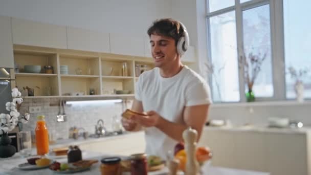 아파트 주방에서 헤드폰에서 요리를 클로즈업 이어폰에서 음악을 식사를위한 토스트를 준비하는 — 비디오