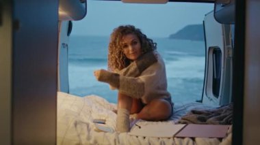 Akşam okyanus kıyısında rahat bir karavan yatağında dinlenen nazik bir bayan. Romantik, güzel bir kadın kasvetli deniz kıyısında karavanda oturuyor. Bayan tatilci, deniz sahilinde hafta sonu yolculuğunun tadını çıkarın.