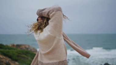 Gezginler bulutlu okyanusun tadını çıkarırlar. Güzel kıyılarda yakın dururlar. Deniz kıyısında dönen gülümseyen kadın kasvetli bir hafta sonunda doğa uyumu hissediyor. Fırtınalı köpüklü dalgalarda poz veren mutlu kıvırcık kadın.