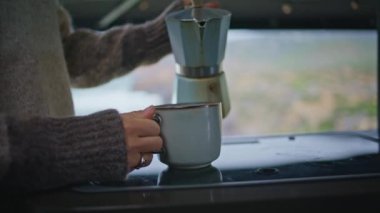 Moka pot 'tan kahve fincanı dolduran kadın elleri karavanın mutfağını kapatın. Tanınmayan bir kadın kahve makinesinden seramik bardağa taze espresso dolduruyor. Bilinmeyen kız karavanda içecek hazırlıyor..