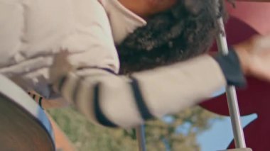 Güneşli çocuk parkında kızıyla kayan neşeli bir kadın. Mutlu gülümseyen Afro-Amerikan annesi oyun sahasında tatlı küçük kızla eğleniyor. Aile hafta sonu aktivitelerini dikey olarak izliyor