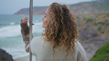 Melankolik kadın, okyanus güzelliğine bakıyor kasvetli kıyılar, yakın plan. Orta yaşlı kıvırcık kadın fırtınalı deniz dalgaları düşünüyor. Haftasonunu kayalık deniz kıyısında geçiriyor. Sakin kadın tatilin tadını çıkar.