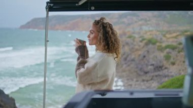 Sabah kadını kahve içiyor ve inanılmaz okyanus dalgalarına bakıyor. Kaygısız kadın turist deniz kıyısındaki karavan terasında espresso yudumluyor. Rahatlamış dişi deniz kıyısında hafta sonu yolculuğunun keyfini çıkar..