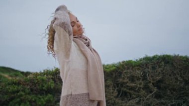 Yalnız kadın bulutlu doğada yürüyor ve yakından bakıyor. Çekici melankolik kadın bulutlu havada güzel kıvırcık saçlara dokunuyor. Düşünceli kadın dinleniyor. Hafta sonunun tadını çıkarıyor.