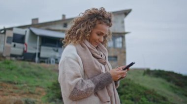 Cep telefonuyla sosyal medyayı izleyen mutlu bir turist kampı kapatıyor. Kıvırcık, olgun bir kadın doğada akıllı telefon mesajı okuyarak gülüyor. Kaygısız bayan cep telefonu video içeriğine bakıyor.