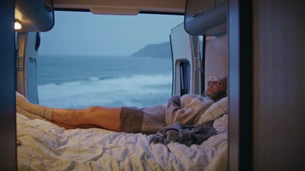 女人喜欢舒适的露营车床 周末晚上在阴暗的海滨度过 在汹涌的海浪中 松驰的卷曲女游客躺在舒适的枕头拖车上 女士在暮色的海岸休息 — 图库视频影像