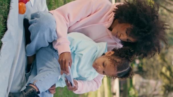 Matka Córka Patrząc Smartfona Siedzi Koc Zewnątrz Szczęśliwa Afroamerykanka Pokazująca — Wideo stockowe