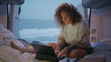 Karavanda sörf yapan uzaktan kumandalı bir işçi akşamları dizüstü bilgisayar ekranına bakıyor. Alacakaranlık 'ta karavanda çalışan serbest çalışan bir kadın. Kıvırcık, ciddi bir bayan bilgisayardan sosyal medya içeriğini izliyor.