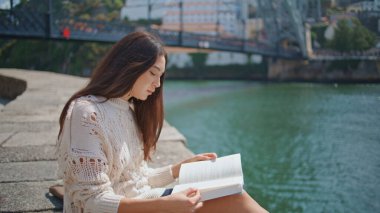 Nehir kenarında kitap okuyan Latin bir bayan. Esmer kız, edebiyatı elinde tutuyor. Sadece Güneş Işıkları Şehri 'nde dinleniyor. Çekici bir kadın saçlarına dokunuyor ve gezinti güvertesinde sakin bir hafta sonu geçiriyor.