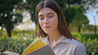 Parkta kitap okuyan düşünceli düşünceli bir kadın huzuru resmediyor. Genç bayan okuyucu, sakin bir açık hava çalışma seansında konsantrasyonunu gösteriyor. Kız öğrenci sakin doğa arka planında romandan zevk alıyor.