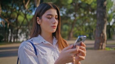 Sunny Park 'ta akıllı telefon yazan düşünceli bir bayan. Yeşil doğada cep telefonuyla mesajlaşan düşünceli bir kadın. Çekici kız cep telefonu ekranına bakıyor. Teknoloji ve sükunet birleşir.
