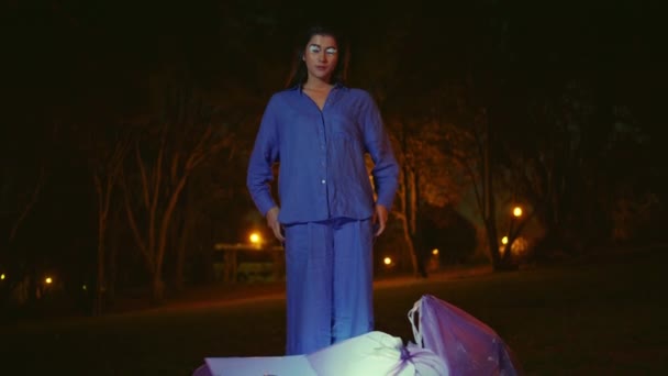 看着环境清洁的女人站在发亮的垃圾袋旁边 美丽的模特穿着蓝色西服 四周环绕着公园的夜色沉静 展示环保意识的时尚表演者 — 图库视频影像
