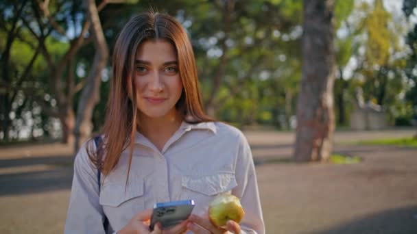Yeşil Güneşli Parkta Elinde Elma Tutan Akıllı Telefonlu Nişanlı Bir — Stok video