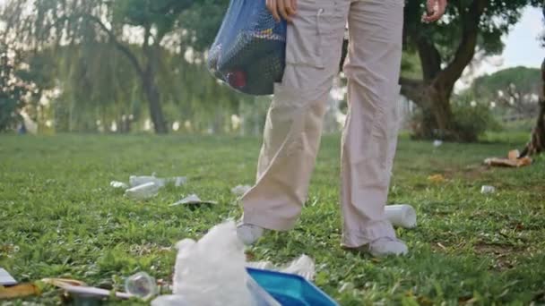 脚踏着被污染的公园在废弃的垃圾堆前行走 自然资源保护主义者的女人踩着自然环境 到处都是塑料垃圾 丢弃青草所带来的环境生态问题 — 图库视频影像