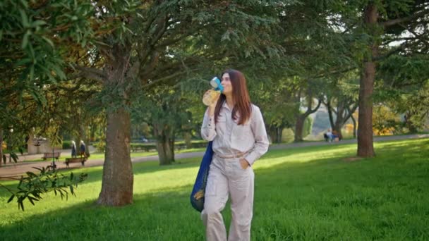 喝酒的女人很享受公园的闲暇 站在绿草上与柠檬水瓶密闭在一起 美丽的金发姑娘在宁静的花园绿地里喝着清爽的饮料 促进健康生活的每日水合作用 — 图库视频影像