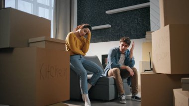 Yorgun eşler eve taşınırken stres hissederler. Oturma odasında karton kutulara bakan yorgun ve evli bir çift. Yeni ipotek evindeki yorgun genç aile kanepede dinleniyor. Emlak yatırımı