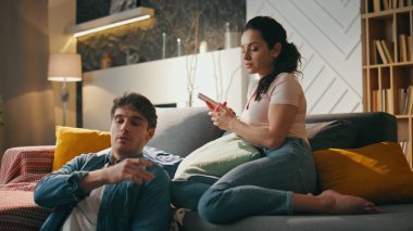 Eşler rahat oturma odasında oturan aletleri konuşuyor. Gülümseyen koca koltukta rahatlamış genç eşe dizüstü bilgisayar ekranı gösteriyor. Mutlu evli çift hafta sonu online alışverişi tartışıyor..