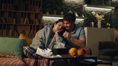 Koca, kanepede oturup sarılan hasta kadını destekliyor. Evdeki oturma odasında ekoseyle kaplı sağlıksız genç eşine bakan sevgi dolu bir adam. Genç erkek arkadaşı evde hasta kız arkadaşını okşuyor..