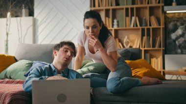 İnternetten alışveriş yapan bir çift dizüstü bilgisayara bakıyor kanepe gibi rahat oturma odasında oturuyor. Genç evli çift evde internet alışverişini tartışıyor. Ürün almak için bilgisayar interneti kullanan rahat milenyumlar.