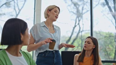 Kahve molasında iş kadınları konuşuyor. Yakın çekim. Pozitif ofis ekibi konferans odasının içinde şakalaşırken eğleniyor. Mutlu genç meslektaşlar grubu dostça iletişim kuruyor. 