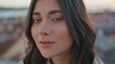 Romantik model şehrin çatısı önünde gökyüzü portresinin önünde poz veriyor. Rahat, esmer görünümlü kamera balkonda yalnız başına dinleniyor. Huzurlu kadın, dinlenme terası. Kasabanın manzarasını inceliyor.