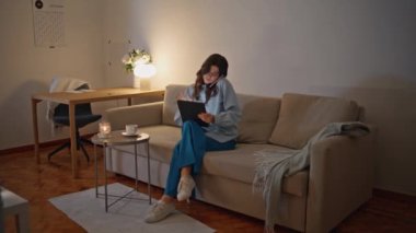 Geç saatte çalışan iş kadını cep telefonuyla konuşuyor. Gece oturma odasında internette internette geziniyor. İşçi odaklı kadın, dijital tableti evde tutarak görüşmeyi bitiriyor. Güzel bayan akşamları çalışıyor. 