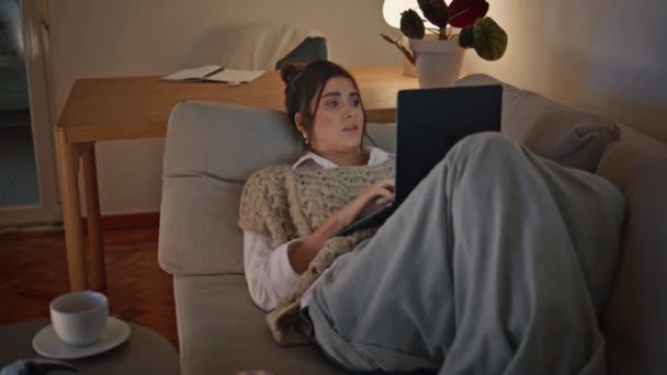 Розслаблена Жінка Розкладає Диван Дивлячись Екран Ноутбука Вечірньому Домашньому Середовищі — стокове відео