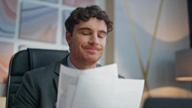 Modern ofiste profesyonel görünümlü kağıtların yakın plan baskısı. İşle ilgili sorunları olan üzgün bir adam masabaşında evrak çalışıyor. Sinirli iş adamı başarısız şirket sonuçlarını analiz ediyor. 