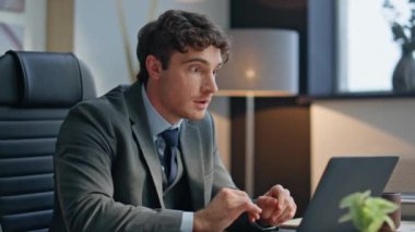 Heyecanlı kazanan iş yerinden memnun, laptopta harika haberler okuyor. Neşeli iş adamı modern ofiste iş başarısını kutlarken mutlu hissediyor. Sevinçten havalara uçmuş girişimci. Sevinç dile getiriyor. 