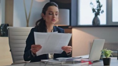 Modern kabine bölgesinde çok düşünceli bir müdürün sözleşme okuması. Ciddi bir iş kadını dizüstü bilgisayarla tek başına çalışıyor. Zarif bayan patron iş belgelerini inceliyor. Gergin hissediyor.